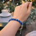 Handmade blue Kumihimo bracelet worn at café table, Caribbean Blue glass seed beads, adjustable clasp artisan jewelry